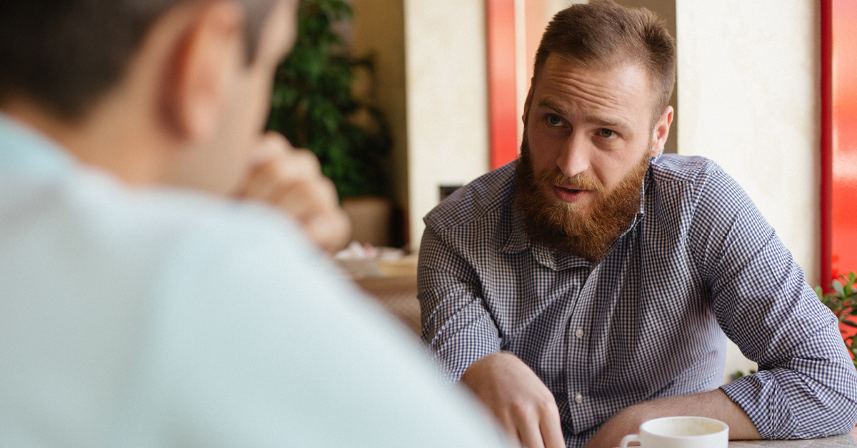 Man talking to another male in a cafe