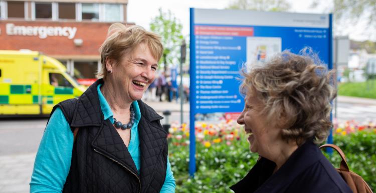 Two older women talking outside of a hospital