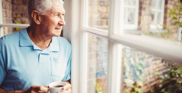 Man looking outside his window with a worried expression