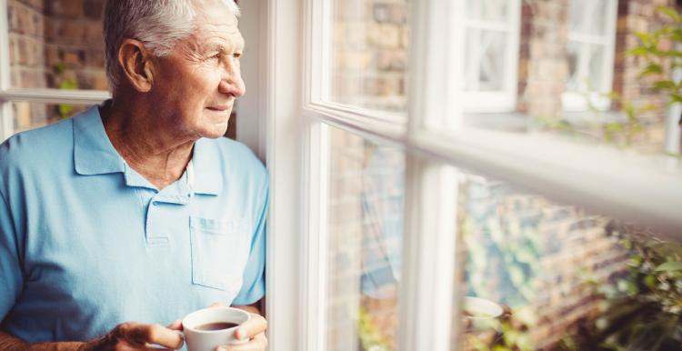 Man looking outside his window with a worried expression