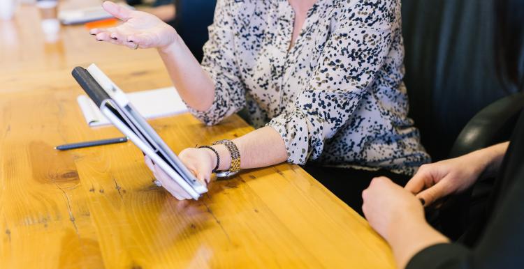 woman holding tablet computer showing to seatmate