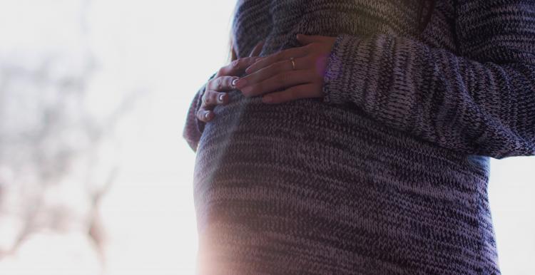 A mother with her hands placed on top of her pregnancy bump