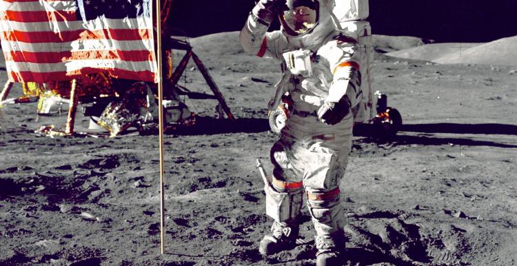 A snapshot from NASA when man took there first few steps on the moon. In the image shows one of the astronauts on the moon, next to the American flag. 