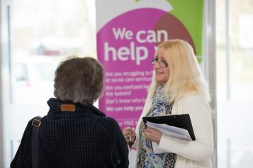 A Healthwatch member smiling at a lady who is talking to her.