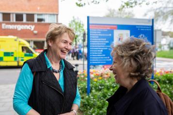 Two older women talking outside of a hospital