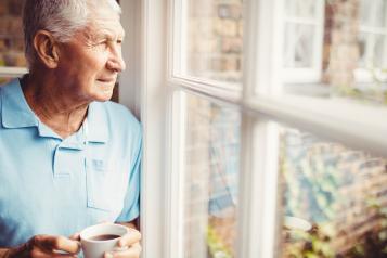 Man looking outside his window with a worried expression