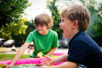 Children playing outside in a paddling pool