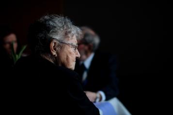 An older lady sitting sitting on stage with other older people