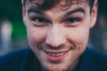 A close up of a brunette man smiling at the camera. 