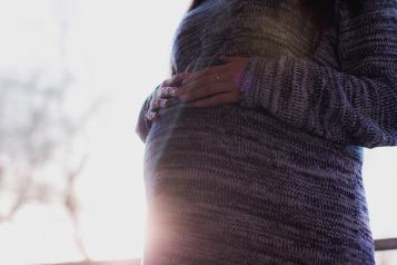 A mother with her hands placed on top of her pregnancy bump