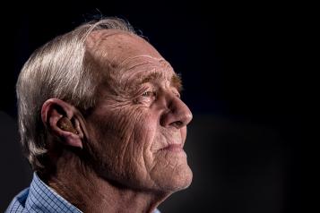 An older man sitting in front of a black background.