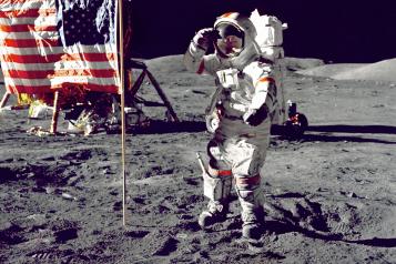 A snapshot from NASA when man took there first few steps on the moon. In the image shows one of the astronauts on the moon, next to the American flag. 