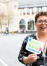 Healthwatch staff member holding an It Starts With You sign to promote the campain