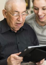 Woman helping an elderly man use a IPad